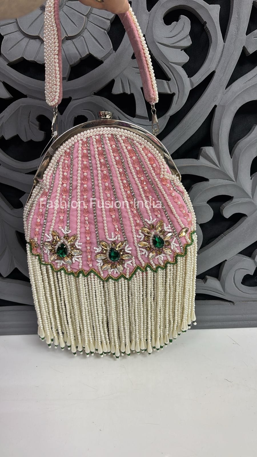 Pink beaded handbag with decorative elements on a white surface with a decorative black and gray background.
