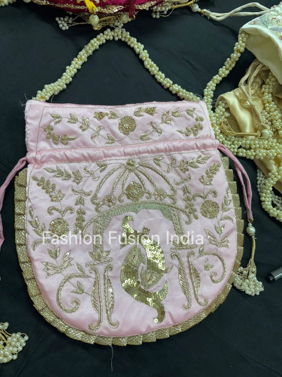 Pink embroidered bag with gold detailing on a dark background, branded 'Fashion Fusion India'.