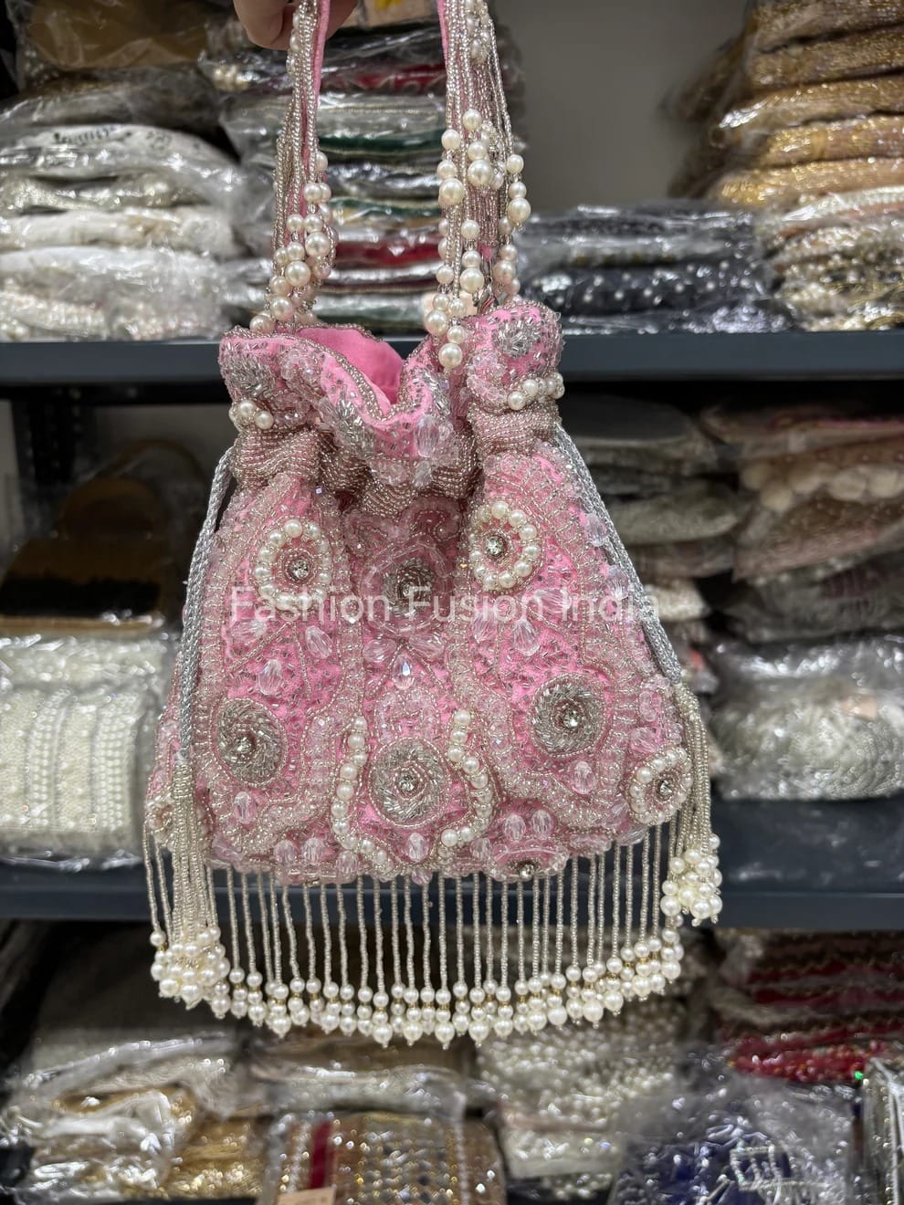 Pink handbag with pearl embellishments in a store setting