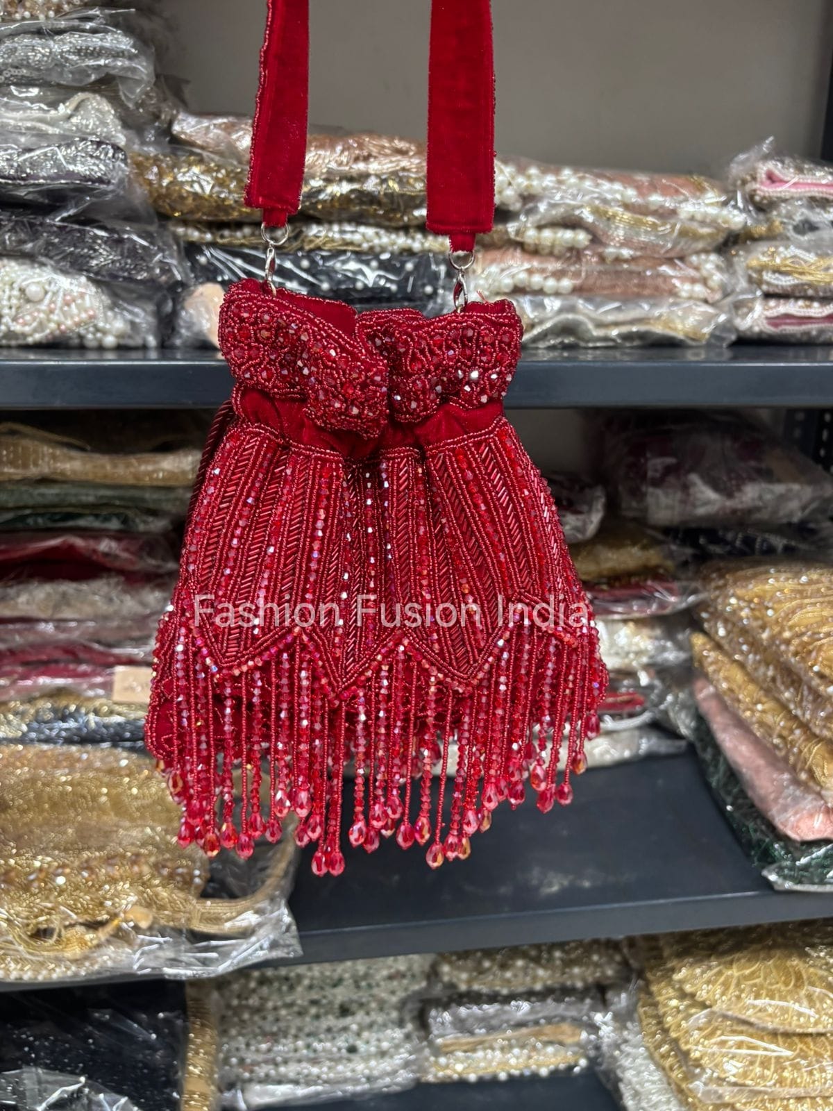 Red beaded handbag with fringe on a shelf with packaging materials in the background