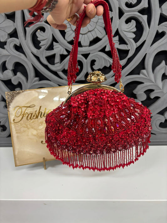 Red beaded handbag held by a hand with a decorative background