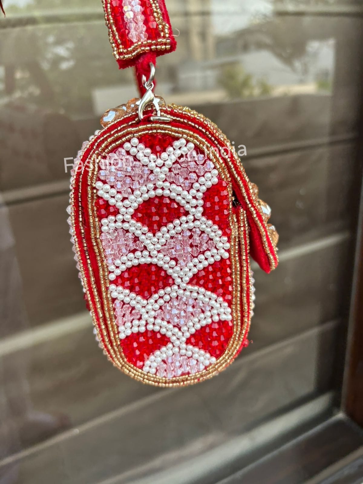 Decorative keychain with red and white pattern on a reflective surface