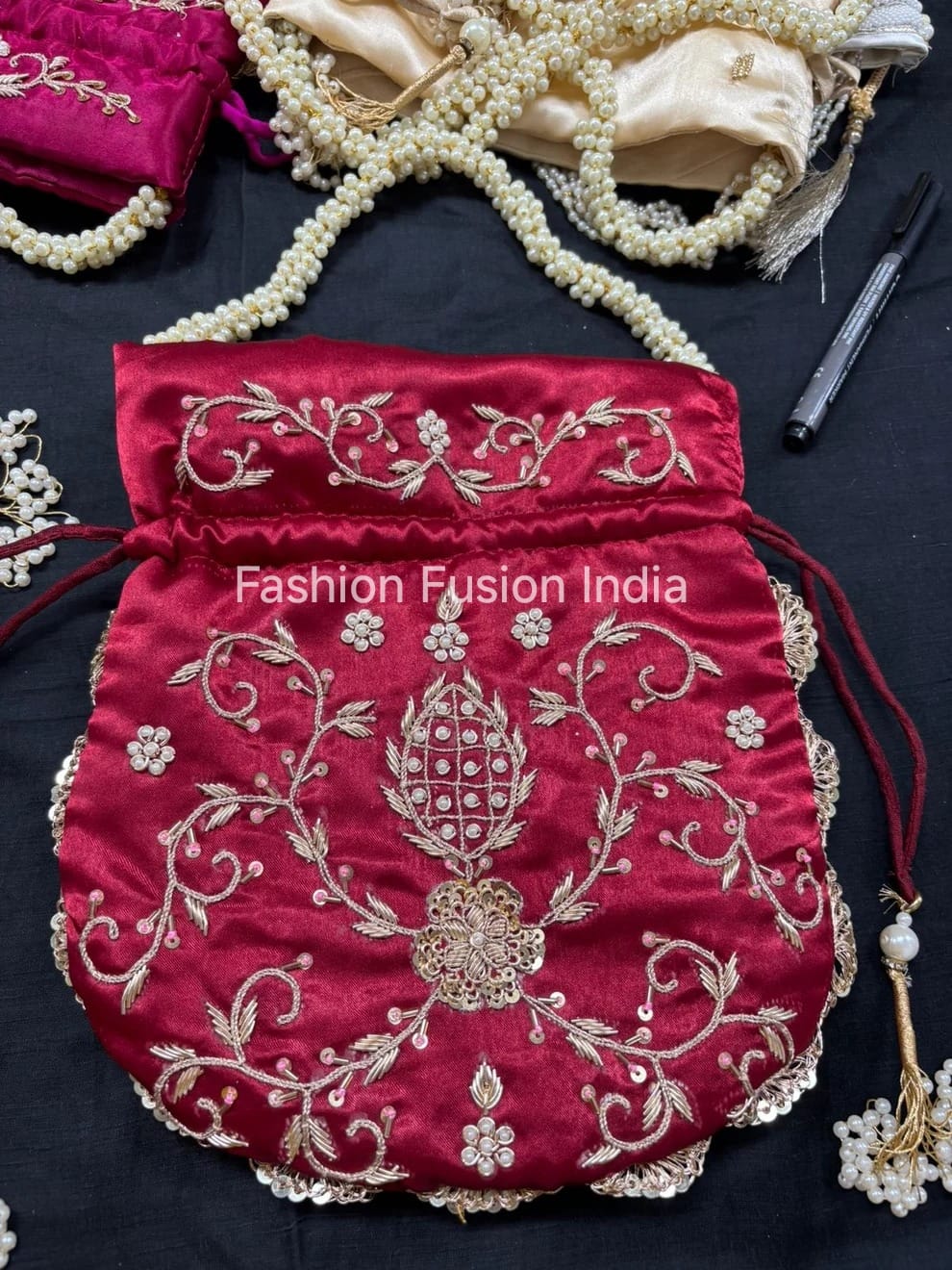 Red embroidered bag with gold detailing on a dark surface, branded 'Fashion Fusion India'.
