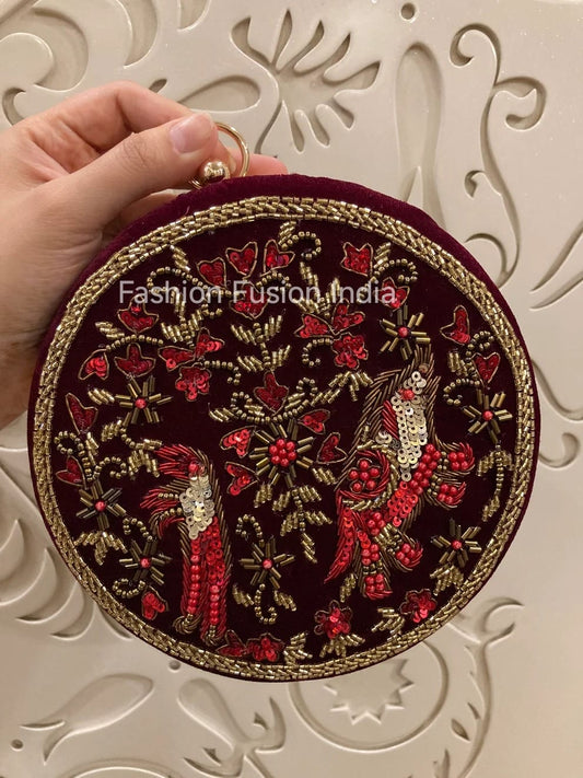 Round embroidered clutch held by a hand against a decorative white background