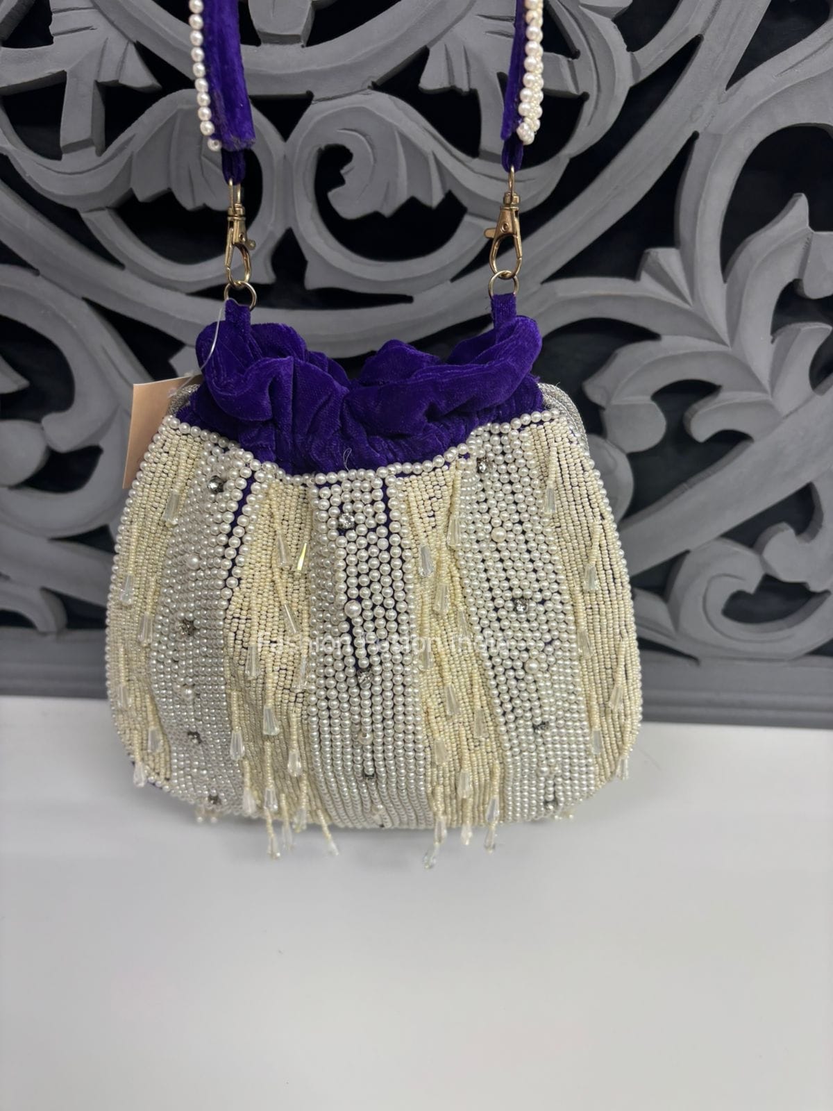 Beaded handbag with purple accents on a shelf with other bags in the background