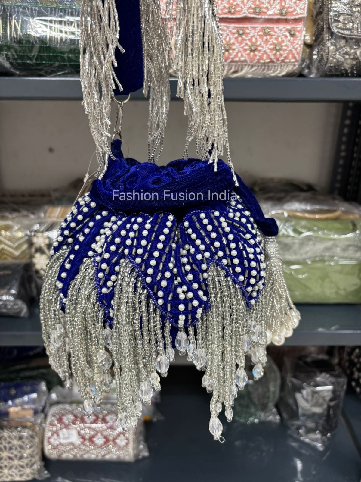 Decorative handbag with blue fabric and silver fringes on a blurred background