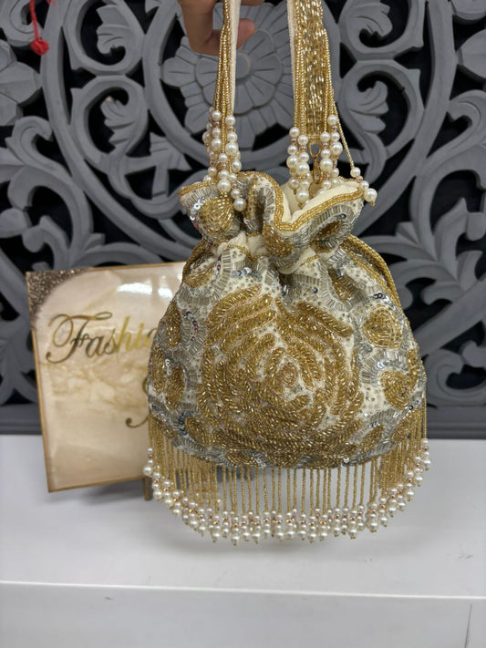 Decorative handbag with pearls and beads on a white surface with a decorative background
