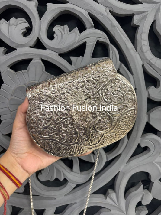 Silver clutch held by a hand with intricate patterns against a decorative background, branded 'Fashion Fusion India'.