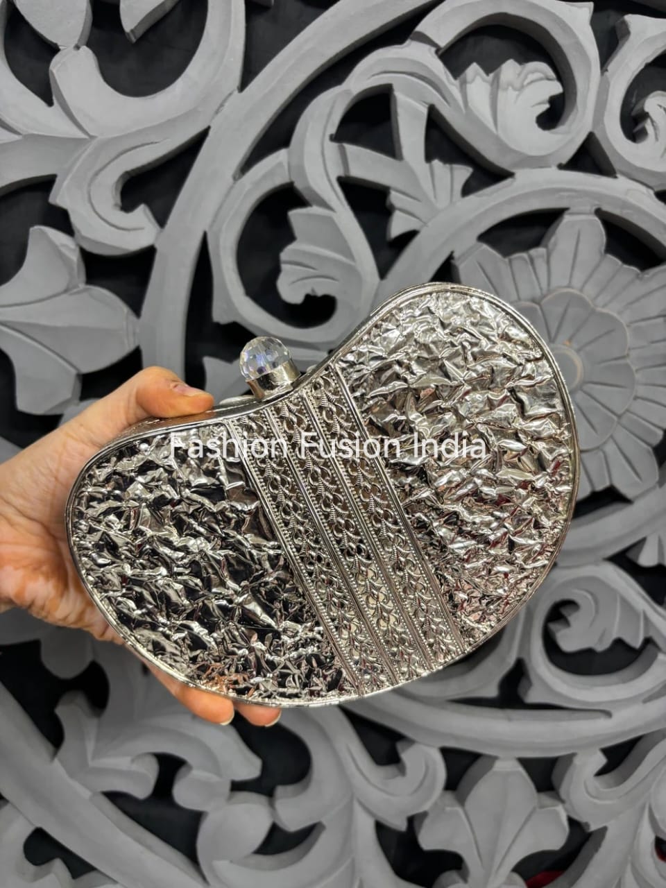 Silver clutch held by a hand against a decorative black and white background with 'Fashion Fusion India' branding.