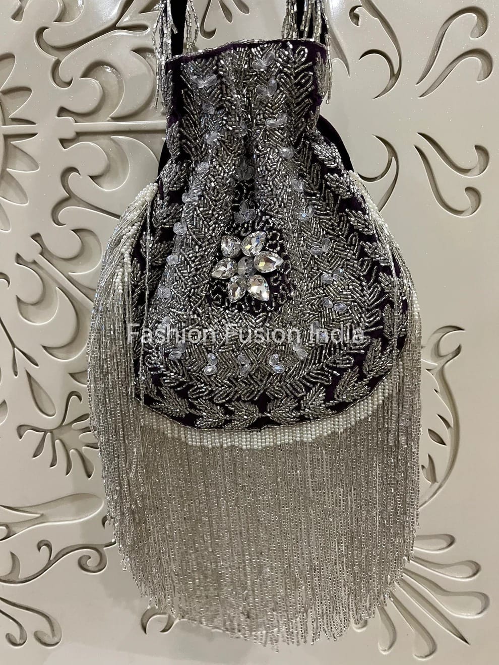 Silver beaded handbag with floral design on a decorative white background
