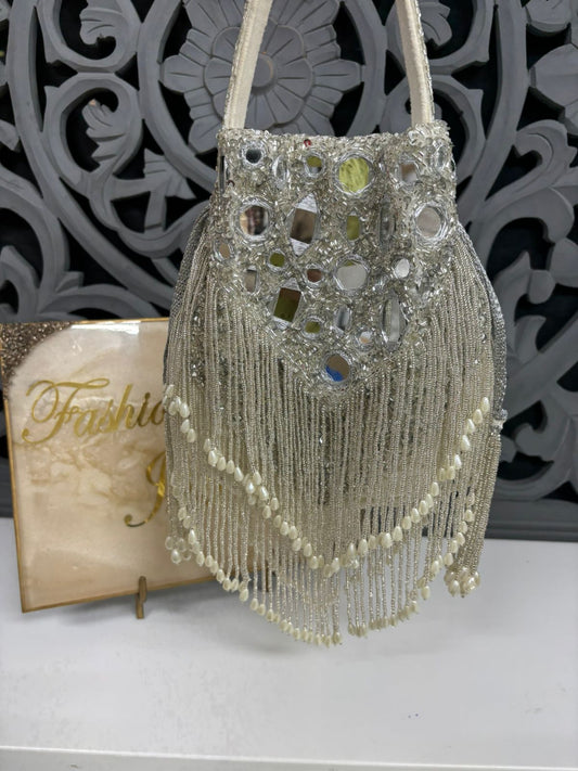 Decorative handbag with beads and mirror-like stones on a textured surface.