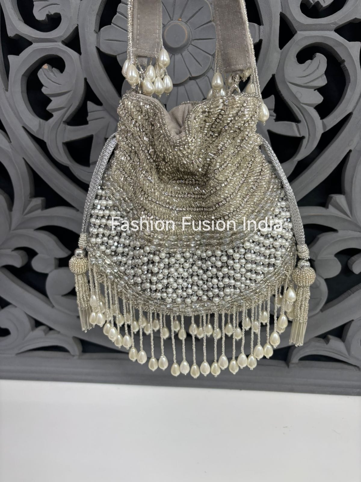 Decorative handbag with beads and tassels against a decorative wall.