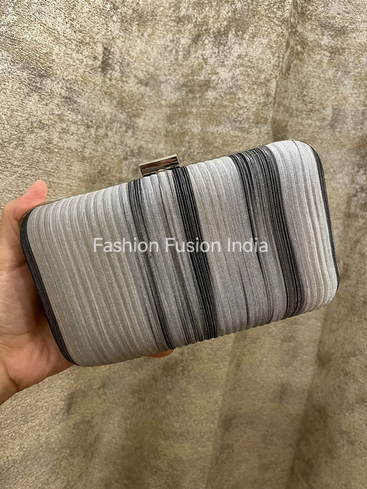 Striped clutch held by a hand on a textured surface with 'Fashion Fusion India' branding.