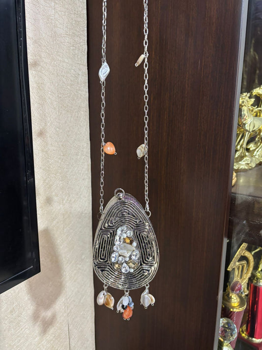 Decorative hanging ornament with beads on a chain against a wooden background