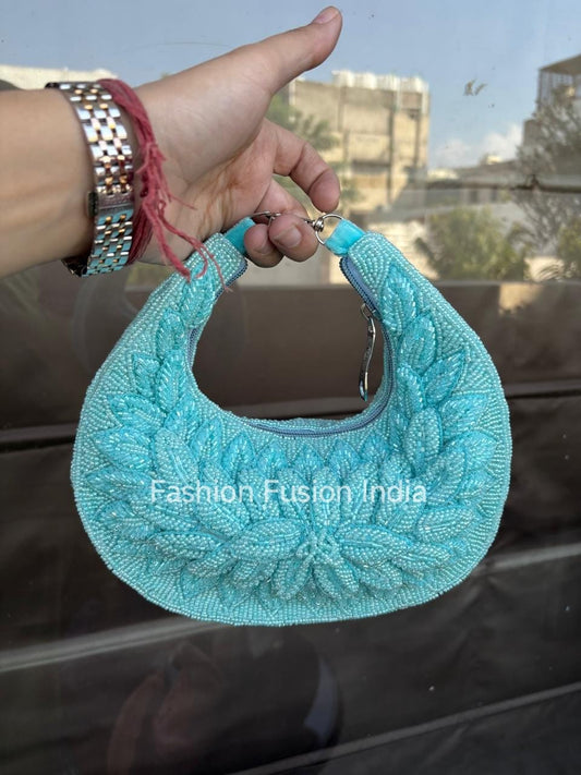 Turquoise handbag held by a hand with a blurred background