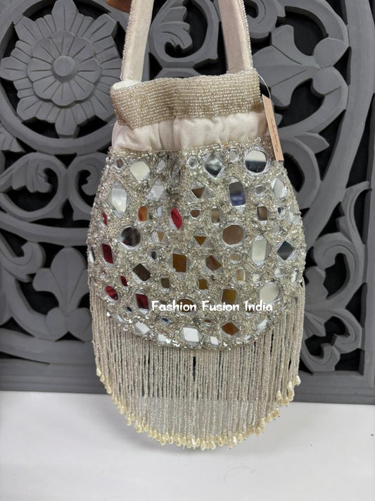 Decorative handbag with mirror embellishments and fringes against a decorative gray background.