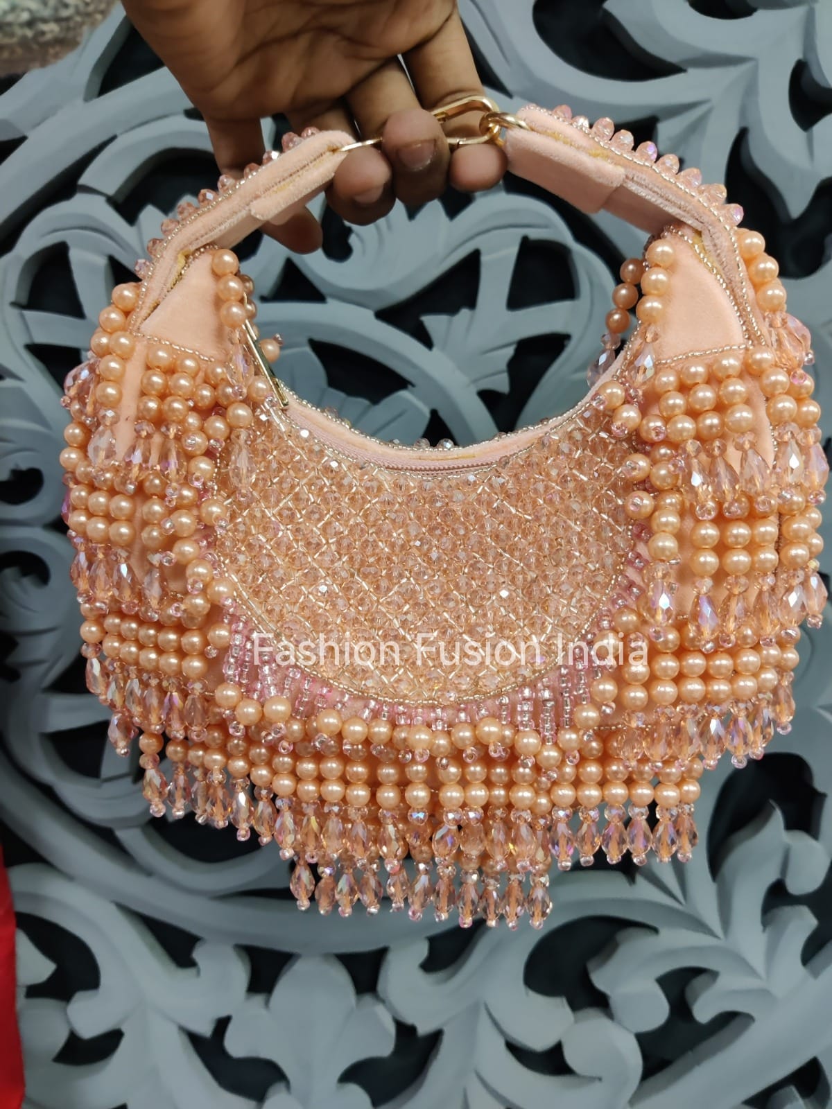 Beaded handbag held by a hand with a decorative background