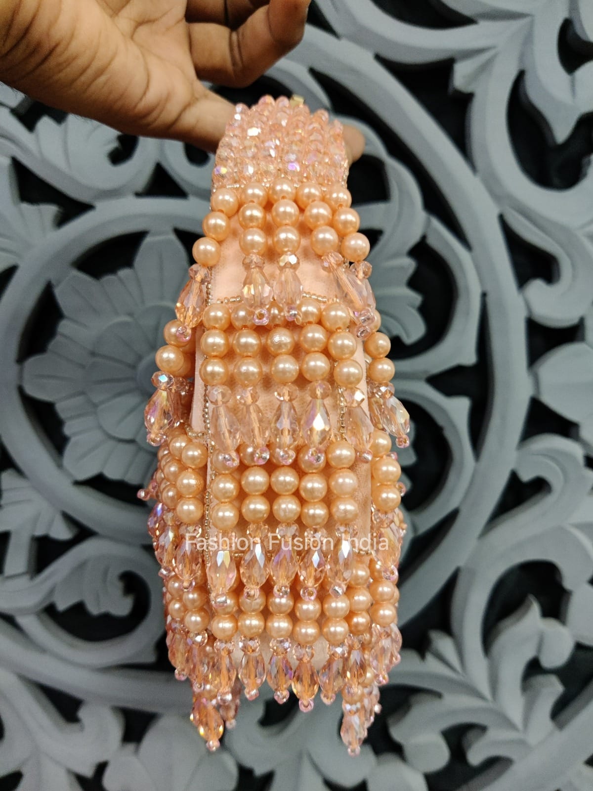 Decorative item made of pearls held by a hand against a decorative background