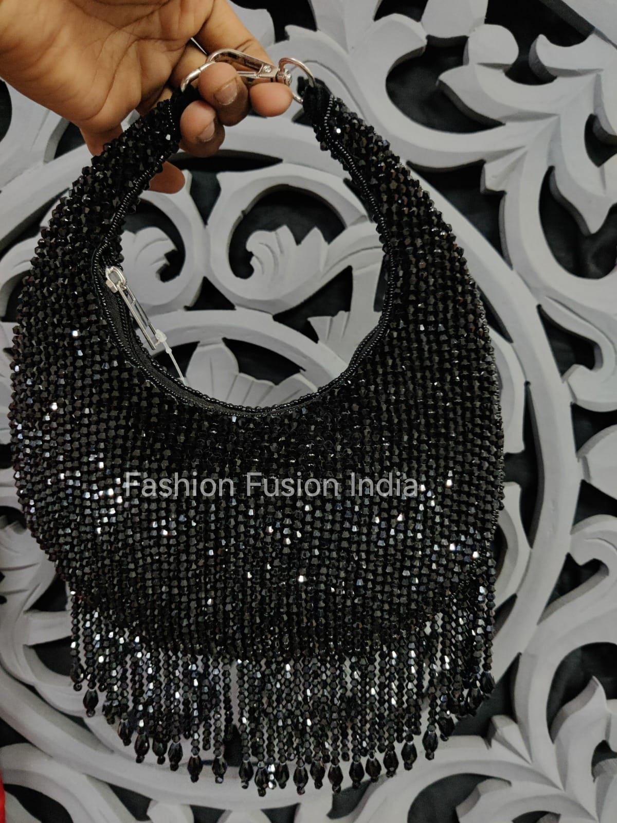 Black beaded handbag held by a hand on a decorative white and black background with 'Fashion Fusion India' branding.