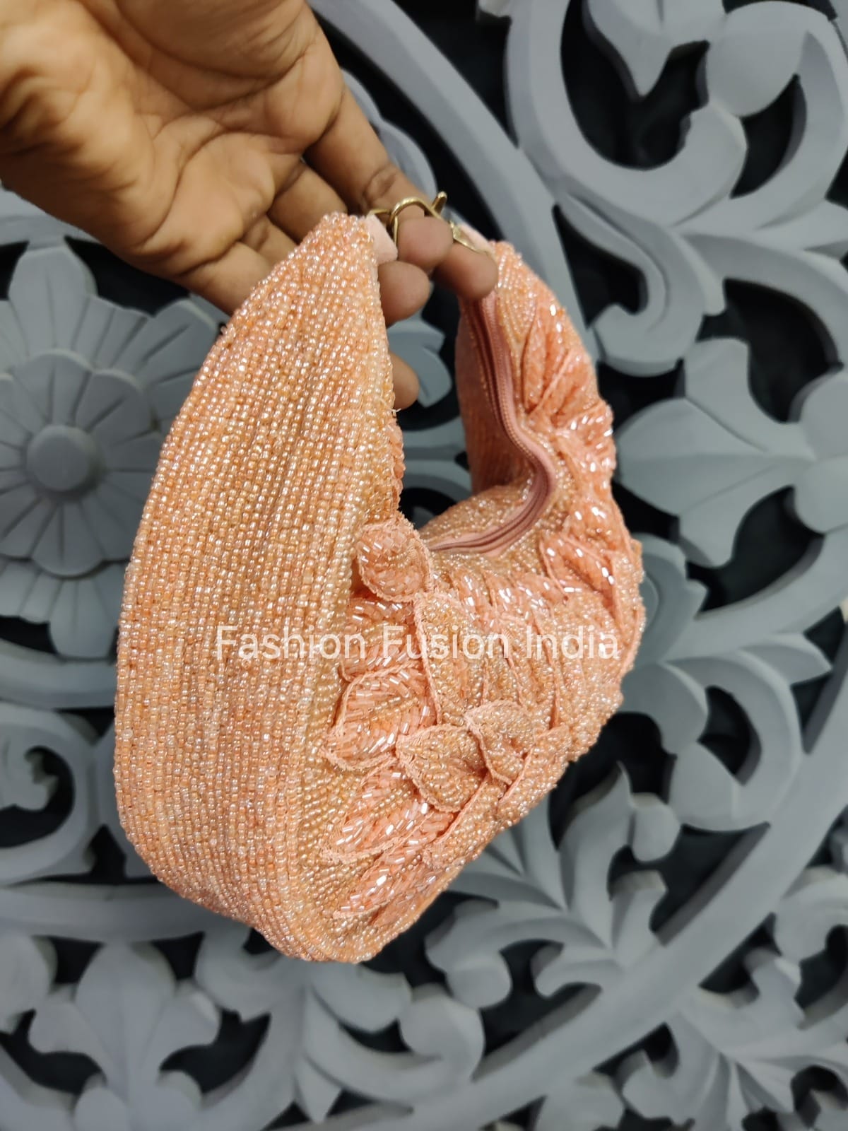 Hand holding a pink beaded clutch against a decorative gray background with 'Fashion Fusion India' branding.