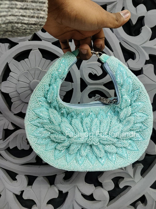 Turquoise beaded handbag held by a hand on a decorative metal surface