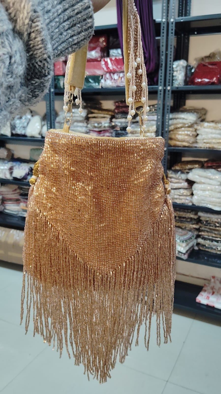 Gold beaded handbag with fringe in a store setting