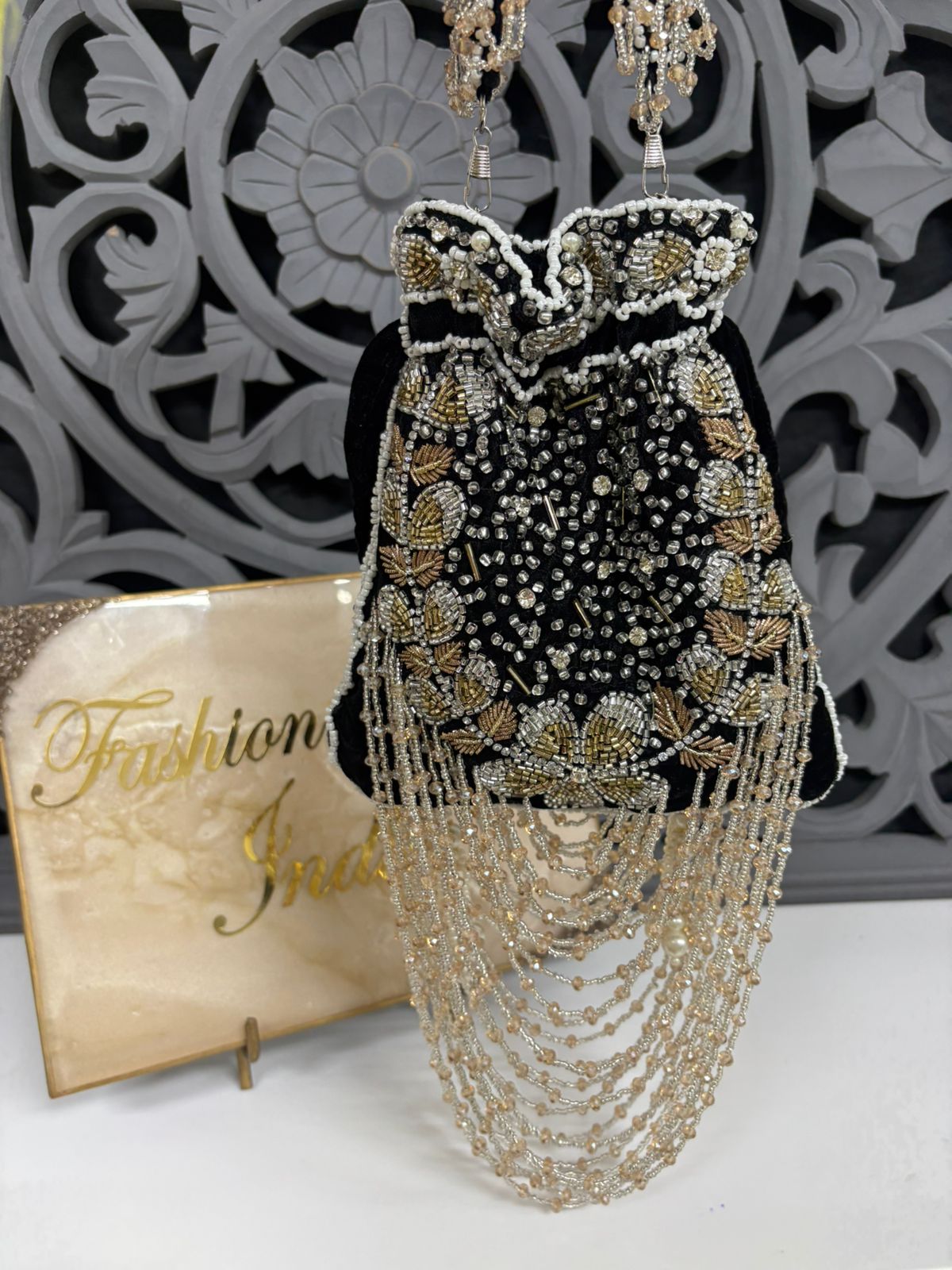 Elegant beaded dress with gold and black details on a mannequin against a decorative wall.