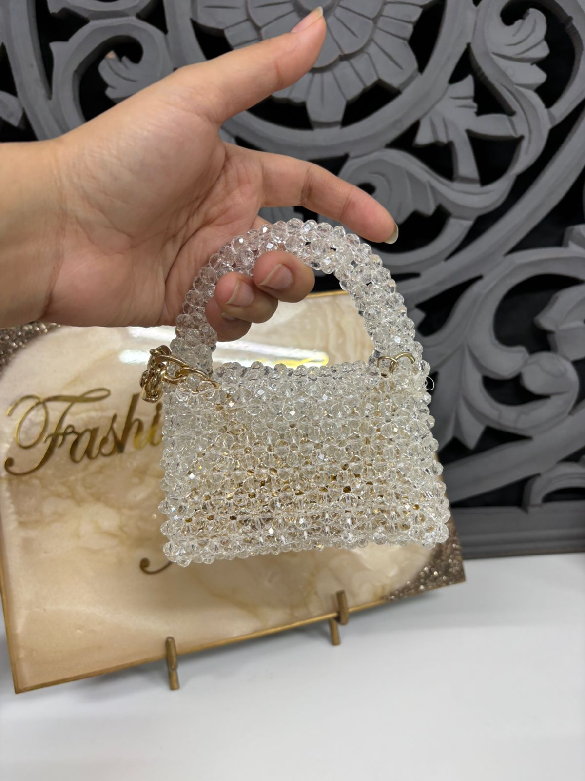 Hand holding a beaded handbag with decorative background