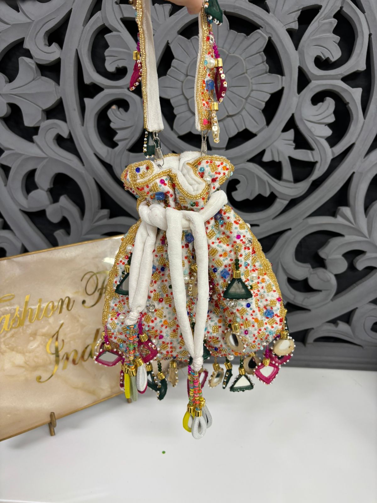 Decorative elephant figurine with colorful patterns and beads against a decorative wall.