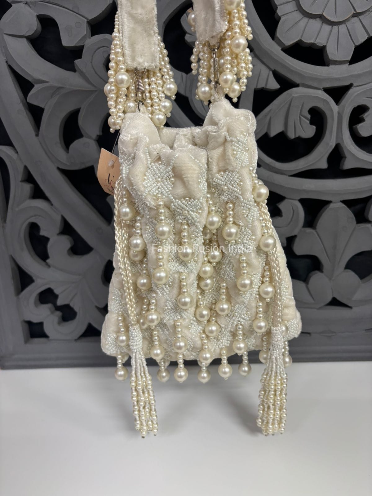 Pearl-handled handbag with decorative elements on a white surface with a gray decorative background