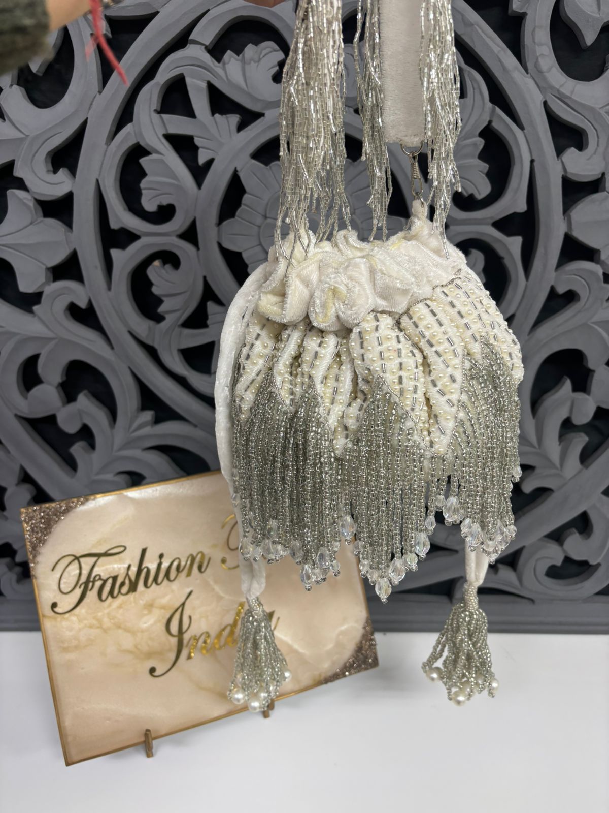 Decorative beaded bag with tassels on a white surface with a decorative background.