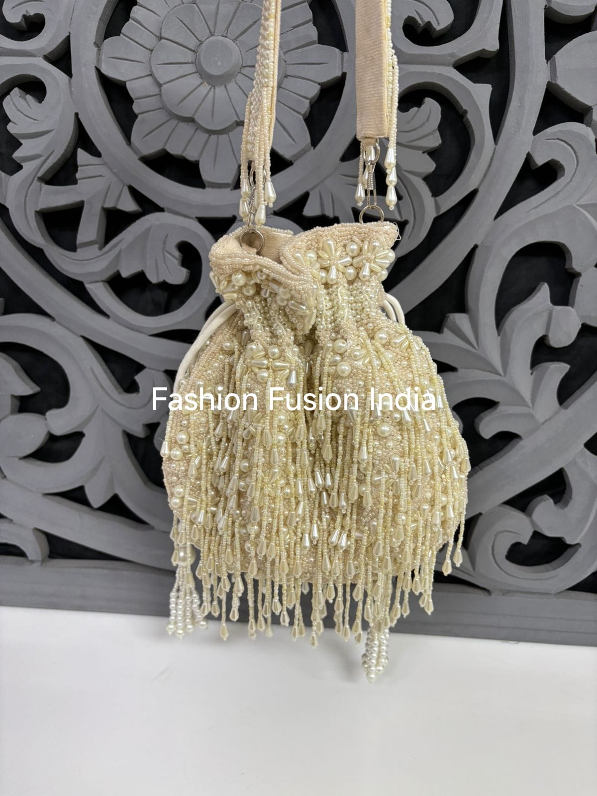 Beaded handbag with fringe details against a decorative wall.