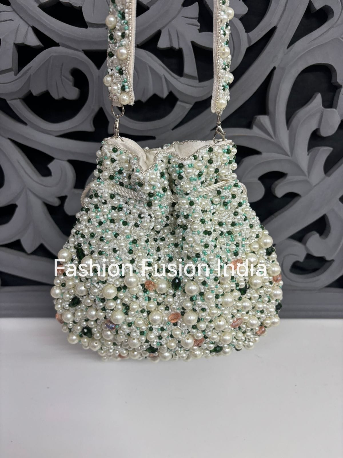 Decorative handbag with pearls and beads on a white surface with a decorative black background.