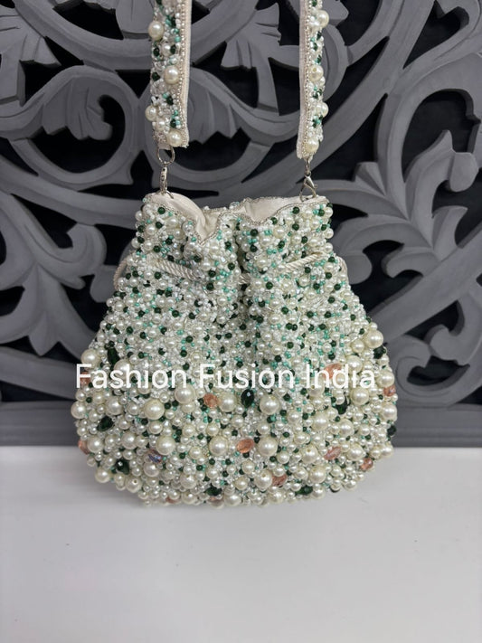 Decorative handbag with pearls and beads on a white surface with a decorative black background.