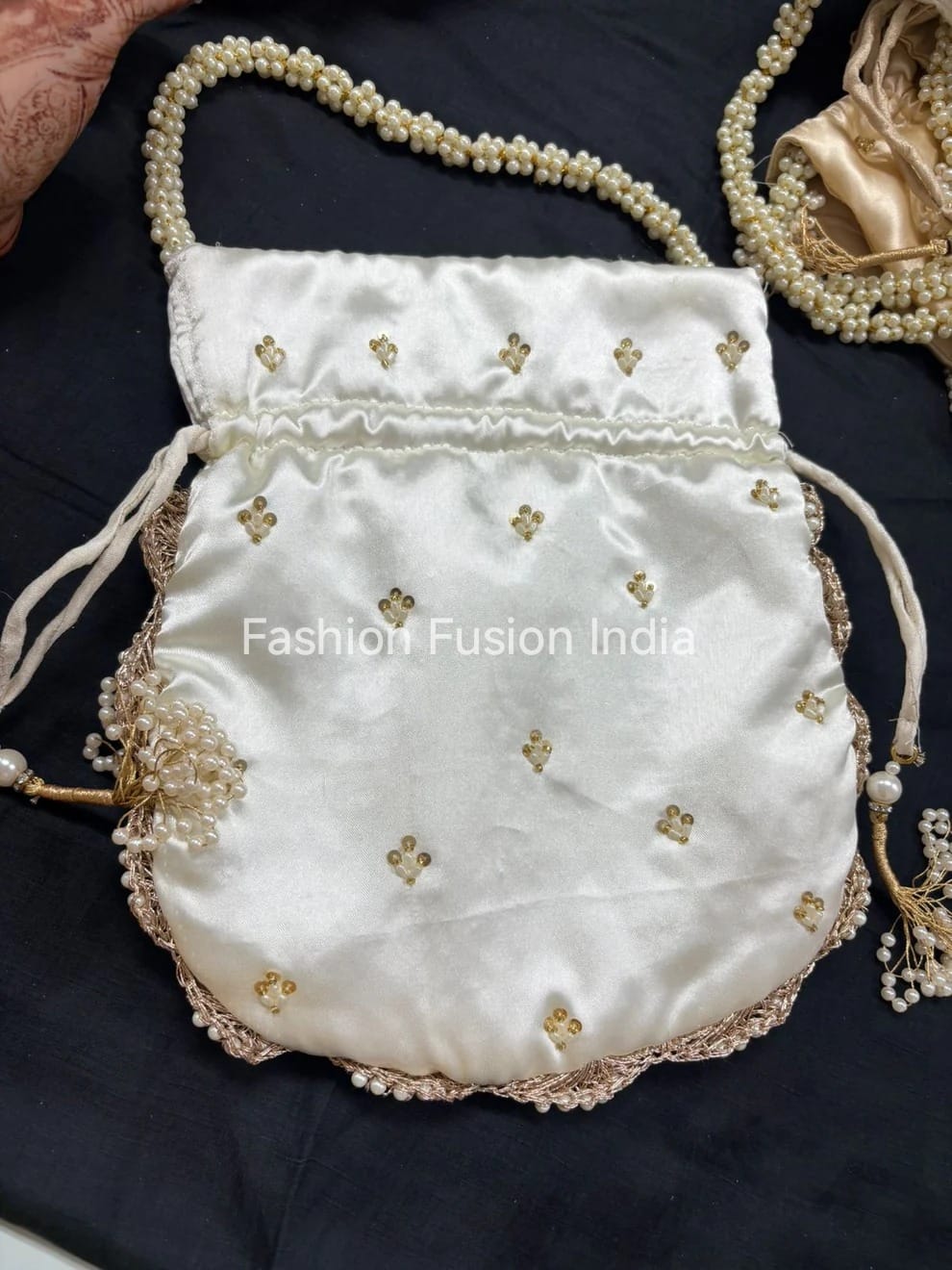 White handbag with gold embroidery and pearl details on a dark background
