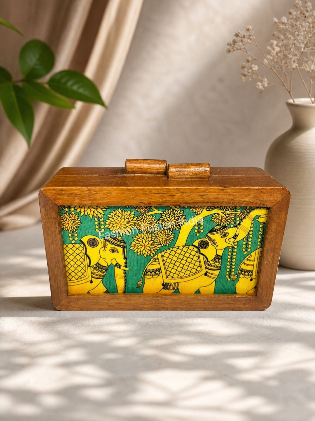 Wooden box clutch with traditional yellow elephant artwork against carved grey backdrop