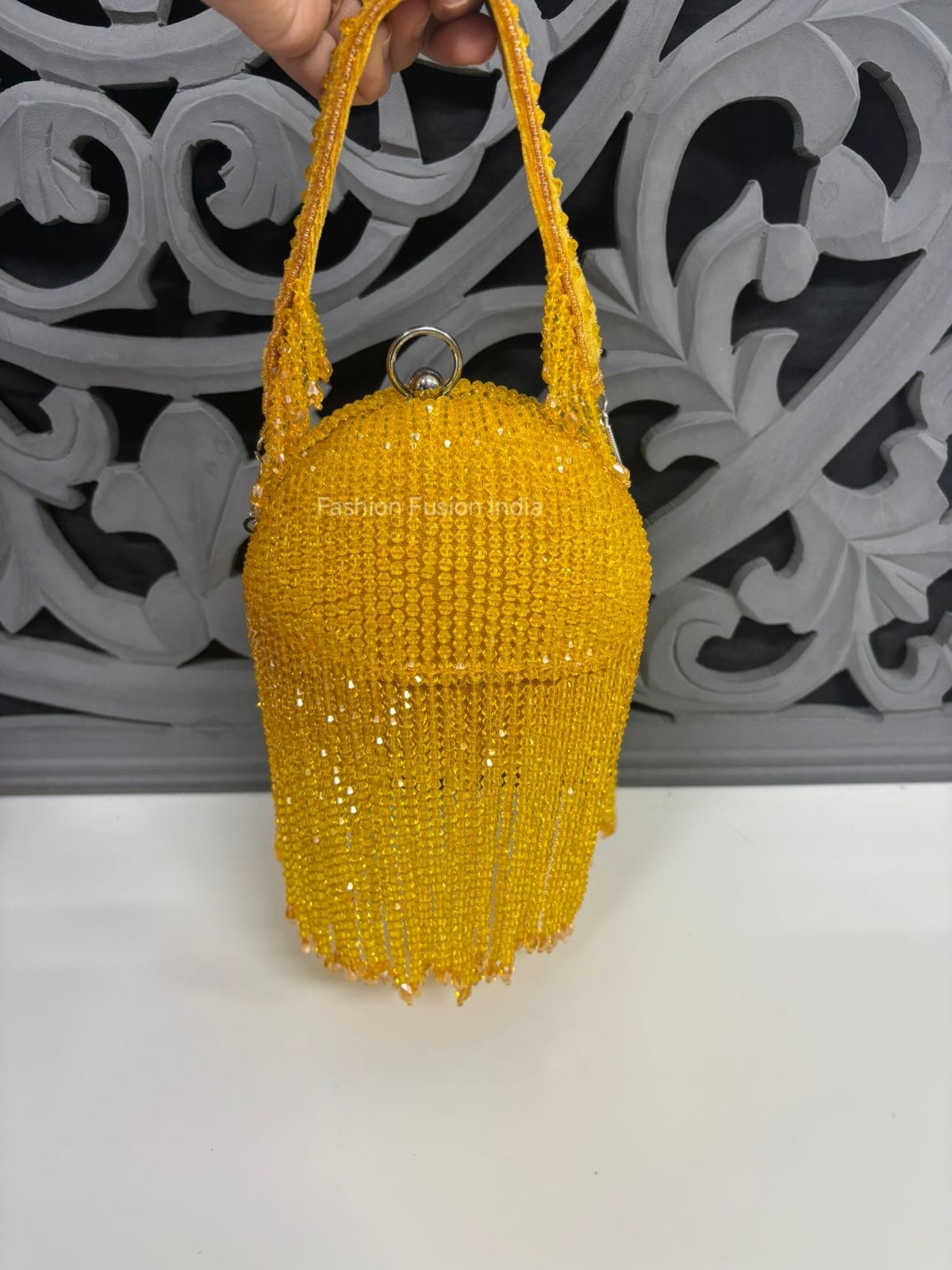 Yellow beaded handbag held against a decorative gray background