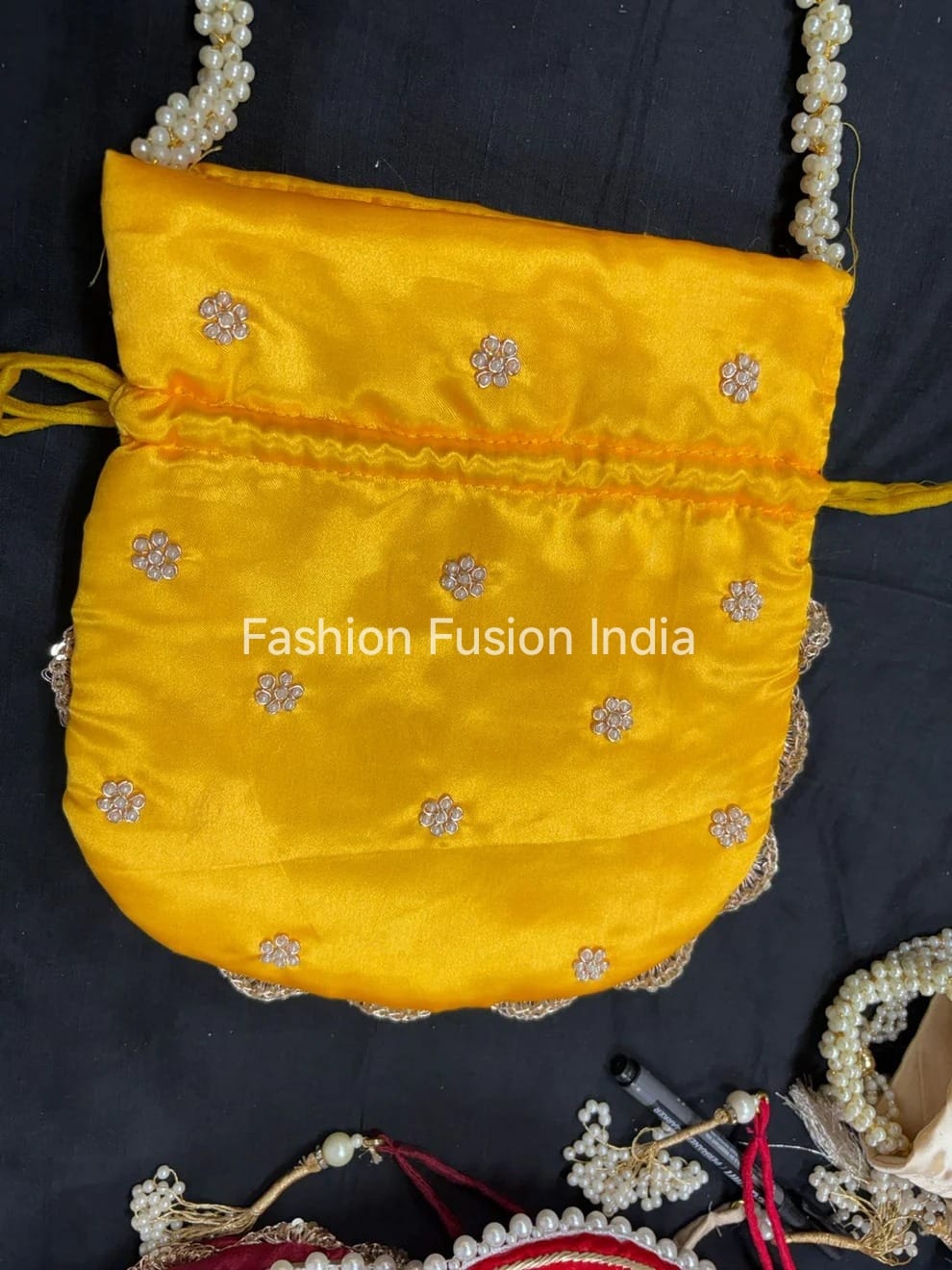 Yellow embroidered bag with pearl details on a dark background