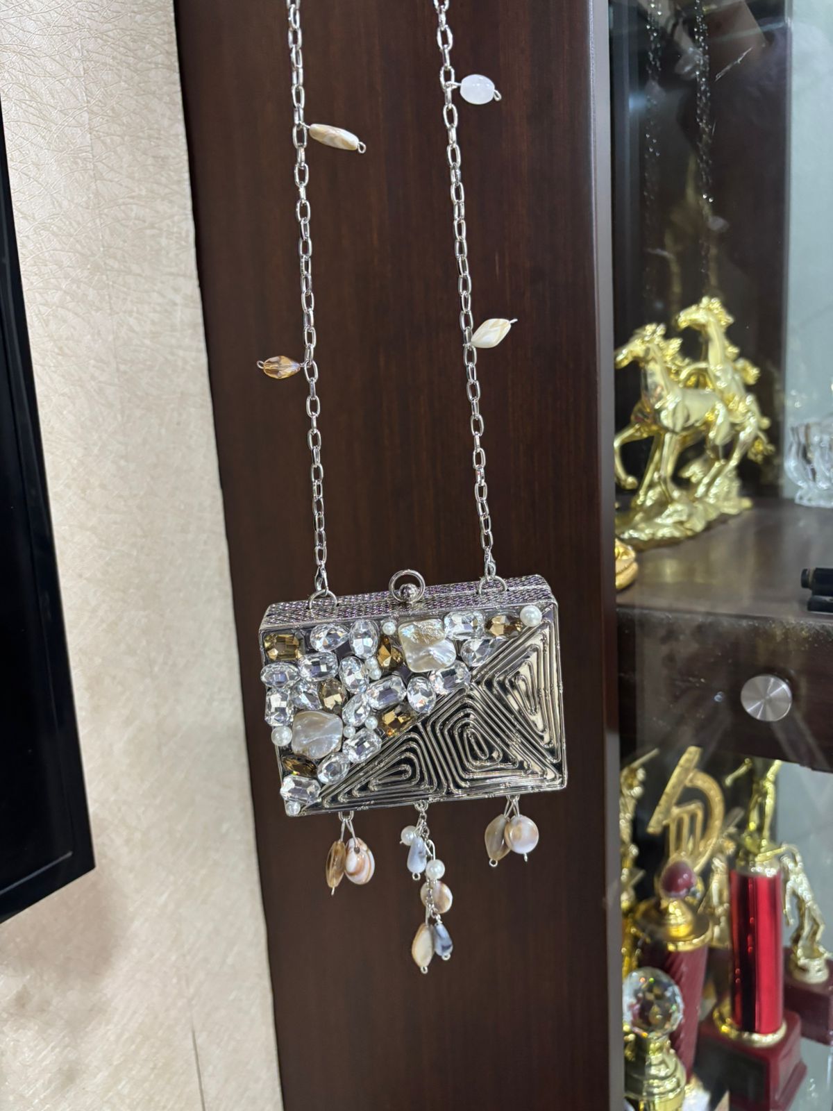 Decorative handbag with embellishments hanging on a wooden surface
