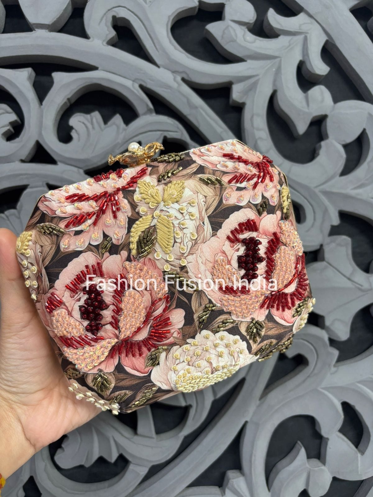 Decorative clutch with floral embroidery held against a decorative background