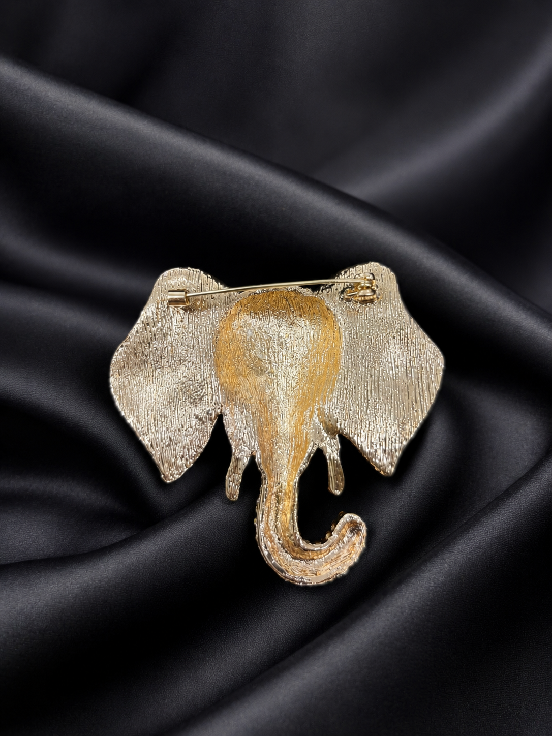 Gold and silver elephant brooch on black satin fabric