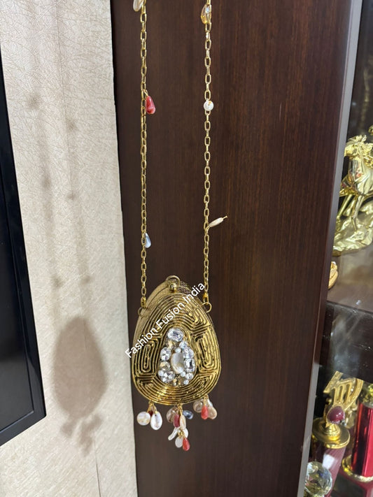 Decorative gold pendant with gemstones on a chain against a wooden background