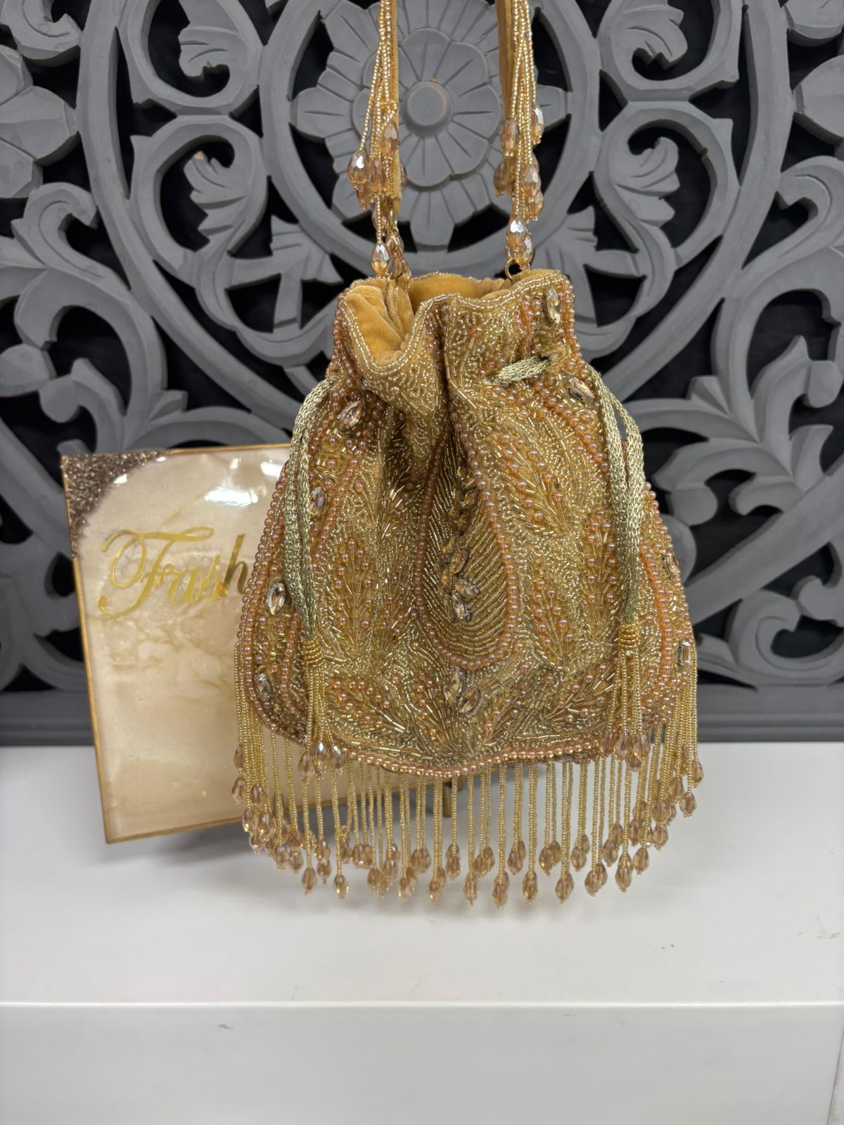 Gold beaded handbag with fringe on a decorative background