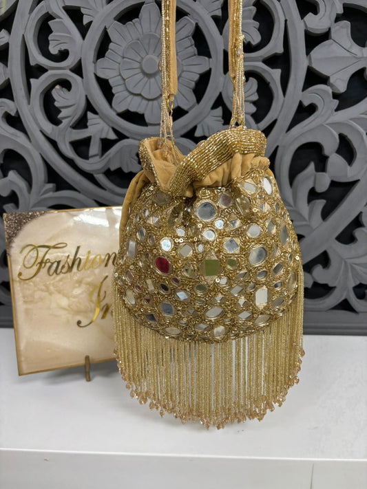 Gold beaded handbag with mirror embellishments on a decorative background