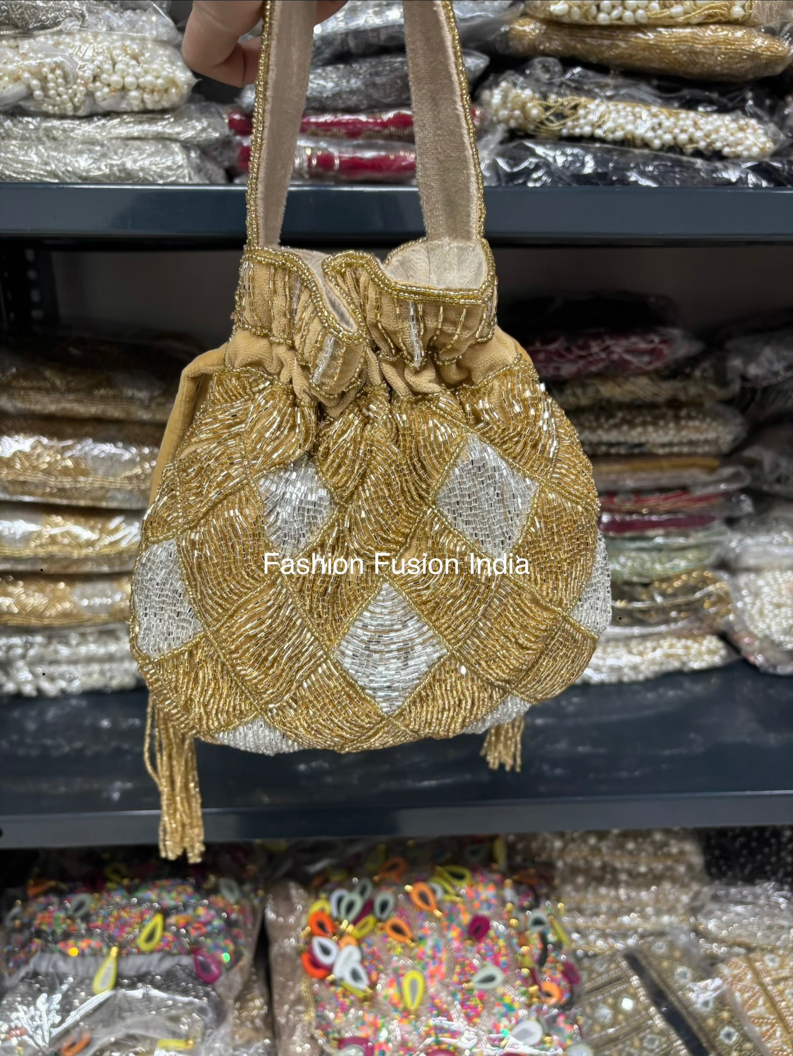 Gold and silver beaded handbag with 'Fashion Fusion India' branding against a blurred background of similar bags.
