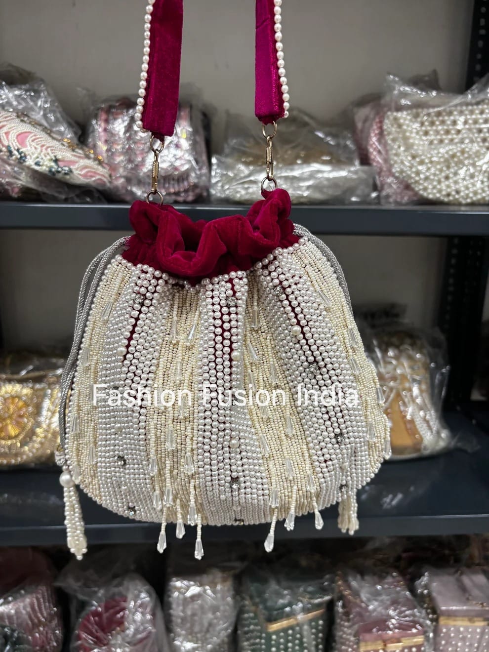 Beaded handbag with hot pink velvet top on a shelf with other bags in the background, labeled 'Fashion Fusion India'.