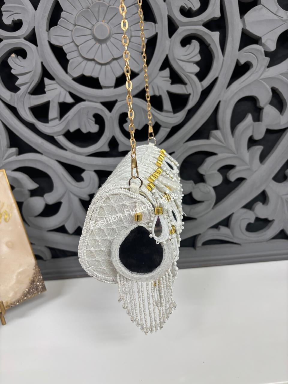 Decorative pendant with beads and a black heart on a gold chain against an ornate gray background.