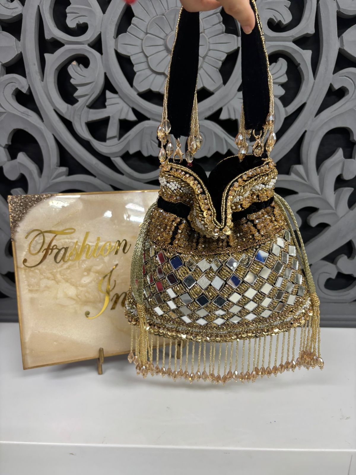 Decorative handbag with intricate designs and a 'Fashion' magazine in the background