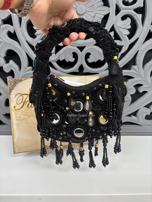 Black beaded handbag held by a hand with a decorative background