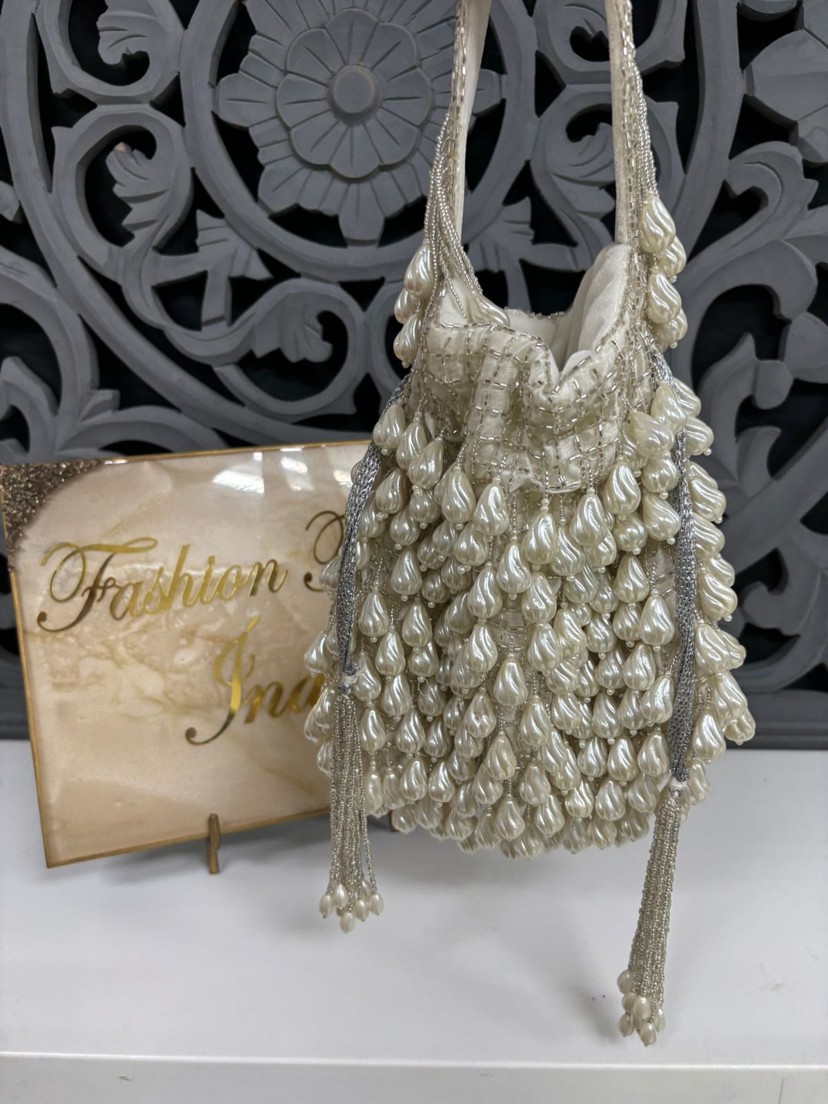 Decorative beaded handbag on a white surface with a decorative background